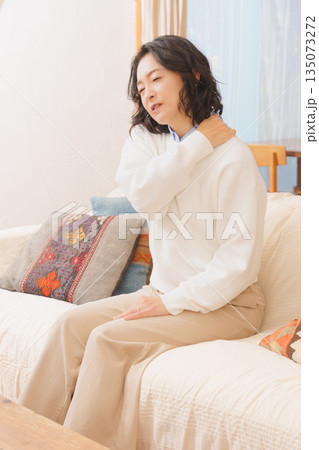 リビングでソファに座り肩をもむミドル女性 リビングでソファに座り肩をもむミドル女性 135073272