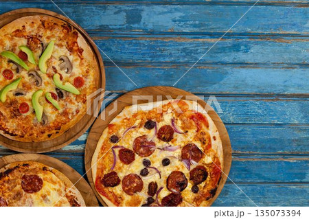 Fresh pizzas on blue wooden table Fresh pizzas on blue wooden table 135073394