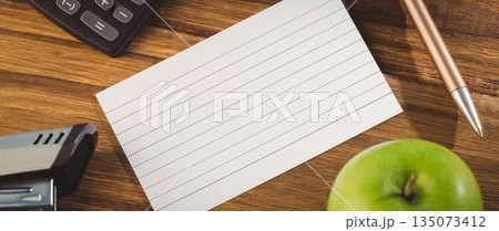 Paper by stapler and calculator with apple on table Paper by stapler and calculator with apple on table 135073412