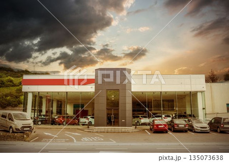 Cars by building against cloudy sky 135073638