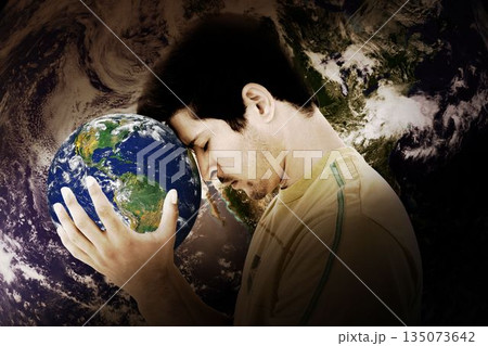 Adult male is pressing forehead against small globe in 3D render cosmic backdrop showing Earth 135073642