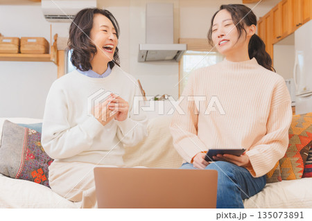 リビングで旅行の打合せをする母娘 リビングで旅行の打合せをする母娘 135073891
