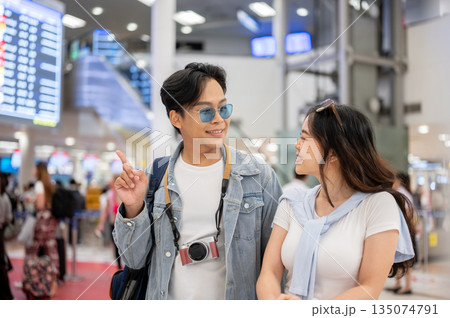 Asian couple man and woman tourist going on a trip walking around waiting for departure in airport. Asian couple man and woman tourist going on a trip walking around waiting for departure in airport. 135074791