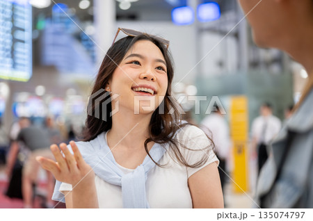 Asian tourist couple woman looking and talking to man going on trip waiting for departure in airport Asian tourist couple woman looking and talking to man going on trip waiting for departure in airport 135074797