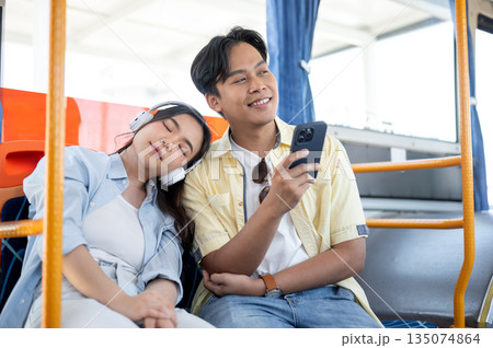 Asian tourist couple on trip woman sleeping on shoulder of man holding phone sitting in shuttle bus Asian tourist couple on trip woman sleeping on shoulder of man holding phone sitting in shuttle bus 135074864