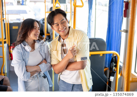 Asian tourist couple crossed arms man talking and pointing aside woman while standing in shuttle bus 135074869
