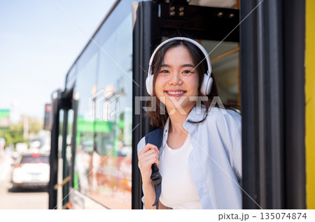 Asian woman tourist holding bag strap while going out or getting off the shuttle bus at stop station Asian woman tourist holding bag strap while going out or getting off the shuttle bus at stop station 135074874