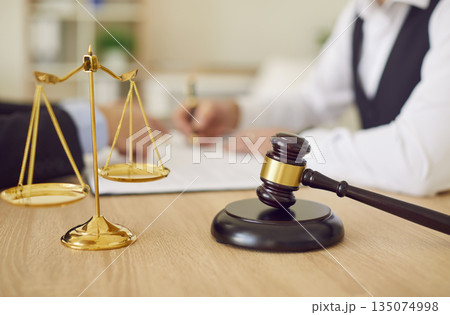 Gavel and scales of justice on table af lawyer giving legal advice in background Gavel and scales of justice on table af lawyer giving legal advice in background 135074998