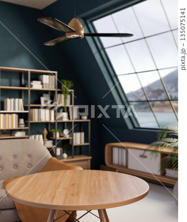 Empty round wood table and chair with bookshelf and roof window with ceiling fan in green attic room 135075141