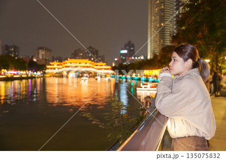 Happy woman traveler travel in Chengdu city. Tourist sightseeing Beautiful Anshun Bridge at night. Famous Landmark for tourism attraction in Sichuan, China 135075832