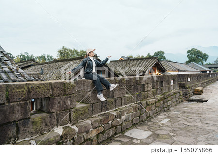 Happy woman traveler travel in Dujiangyan city. Tourist sightseeing the Ming City Wall at Guanxian Ancient City near Chengdu. Landmark and popular for tourism attraction in Sichuan, China 135075866