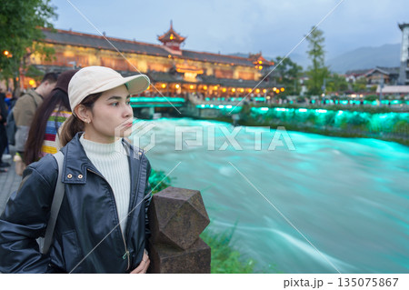 Happy woman traveler travel in Chengdu city. Tourist sightseeing Dujiangyan irrigation system consists of Nanqiao and Langqiao Bridge near ancient city of Guanxian, Sichuan, China Happy woman traveler travel in Chengdu city. Tourist sightseeing Dujiangyan irrigation system consists of Nanqiao and Langqiao Bridge near ancient city of Guanxian, Sichuan, China 135075867