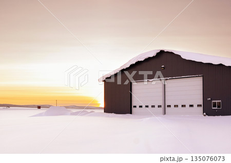Warehouse in snow, industrial building in sunset light in winter. Warehouse in snow, industrial building in sunset light in winter. 135076073
