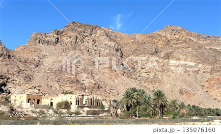 Silent Mountain Refuge, Arid Hillside Settlement View, Peaceful Desert Oasis Among Steep Rocky Cliffs And Sunlight, Serene Mountainous Retreat Surrounded By Lush Palms And Illuminated By Bright Sun Silent Mountain Refuge, Arid Hillside Settlement View, Peaceful Desert Oasis Among Steep Rocky Cliffs And Sunlight, Serene Mountainous Retreat Surrounded By Lush Palms And Illuminated By Bright Sun 135076160