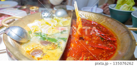 Woman tourist eating traditional hot pot or mala spicy soup in restaurant. Popular foods for tourist eating in Chengdu, Chongqing and China. Chinese Asia and Sichuan foods concept Woman tourist eating traditional hot pot or mala spicy soup in restaurant. Popular foods for tourist eating in Chengdu, Chongqing and China. Chinese Asia and Sichuan foods concept 135076262