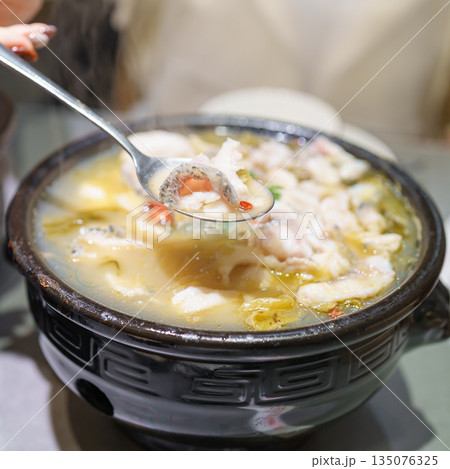 Woman tourist eating Sichuan Fish with Pickled Mustard Greens or Suan Cai Yu in restaurant. Popular foods for tourist eating in Chengdu, Chongqing and China. Chinese Asia and Sichuan foods concept 135076325