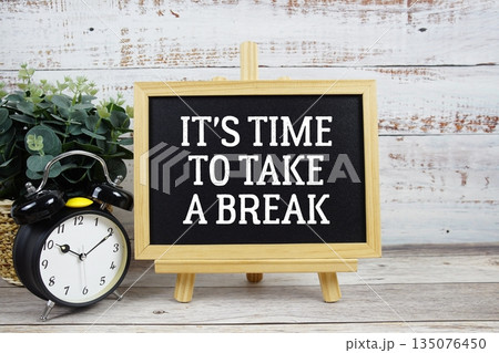It's time to take a break text written on blackboard with alarm clock on wooden background It's time to take a break text written on blackboard with alarm clock on wooden background 135076450