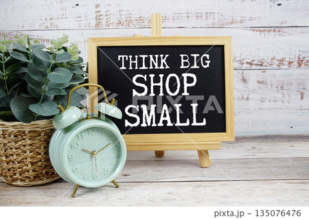 Think Big Shop Small text written on blackboard with alarm clock on wooden background Think Big Shop Small text written on blackboard with alarm clock on wooden background 135076476