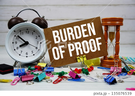 Burden Of Proof text on paper card with alarm clock and stationary on wooden background Burden Of Proof text on paper card with alarm clock and stationary on wooden background 135076539