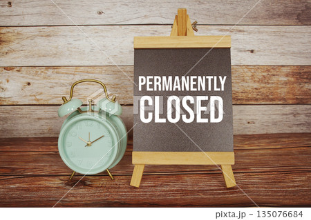 Permanently Closed text on easel blackboard with alarm clock on wooden background Permanently Closed text on easel blackboard with alarm clock on wooden background 135076684