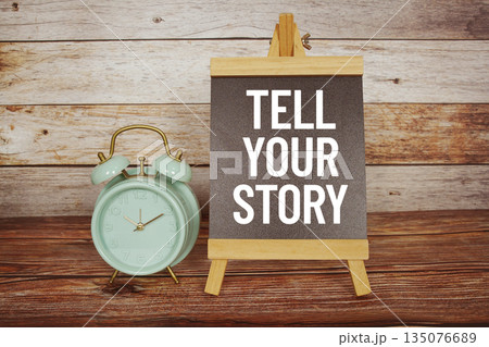Tell Your Story text on easel blackboard with alarm clock on wooden background Tell Your Story text on easel blackboard with alarm clock on wooden background 135076689