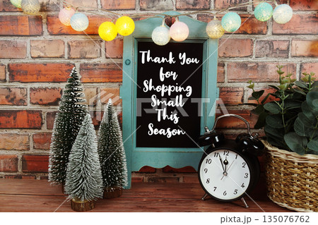 Thank You for Shopping Small This Season text written on easel with alarm clock and pine three Thank You for Shopping Small This Season text written on easel with alarm clock and pine three 135076762