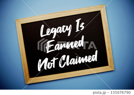 Legacy Is Earned Not Claimed text written on chalkboard flat lay on blue background 135076790