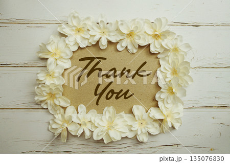 Thank You text written on paper card with flower decoration on wooden background Thank You text written on paper card with flower decoration on wooden background 135076830