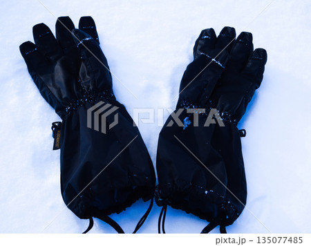 雪原に置かれた黒いスキーグローブ：冬のアウトドアとウィンタースポーツのイメージ 135077485