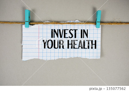 Invest In Your Health text written on rip paper with wooden clip on beige background 135077562