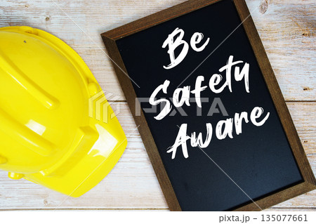 Be Safety Aware text written on blackboard with safety helmet on wooden background 135077661