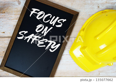 Focus On Safety text written on blackboard with safety helmet on wooden background 135077662