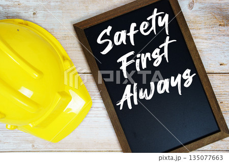 Safety First Always text written on blackboard with safety helmet on wooden background Safety First Always text written on blackboard with safety helmet on wooden background 135077663