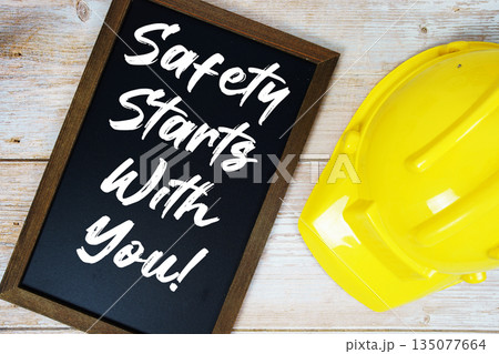 Safety Starts With You! text written on blackboard with safety helmet on wooden background Safety Starts With You! text written on blackboard with safety helmet on wooden background 135077664