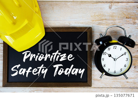 Prioritize Safety Today text written on blackboard with safety helmet and alarm clock on wooden background Prioritize Safety Today text written on blackboard with safety helmet and alarm clock on wooden background 135077671