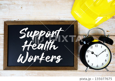 Support Health Workers text written on blackboard with safety helmet and alarm clock on wooden background 135077675