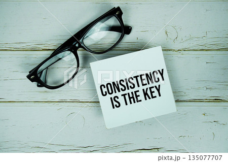 Consistency Is The Key text with eyeglasses on wooden background Consistency Is The Key text with eyeglasses on wooden background 135077707