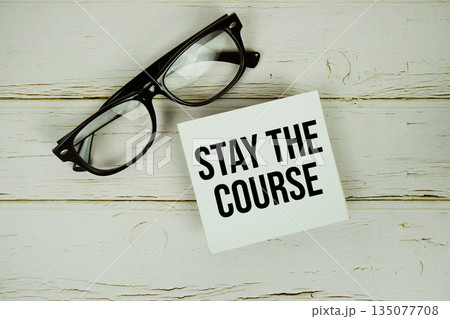 Stay The Course text with eyeglasses on wooden background 135077708