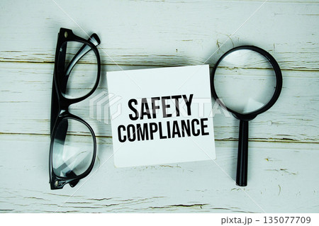 Safety Compliance text with eye glasses and magnifying glass on wooden background 135077709