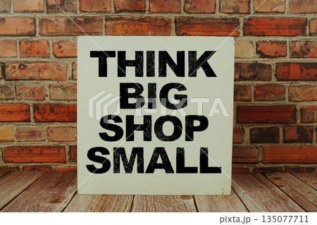 Think Big Shop Small text written on wooden board standing with old brick wall background Think Big Shop Small text written on wooden board standing with old brick wall background 135077711