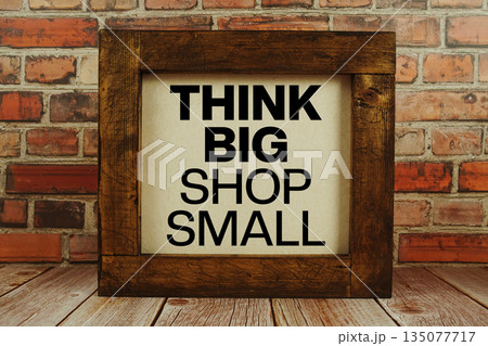 Think Big Shop Small text written on wooden board standing with old brick wall background Think Big Shop Small text written on wooden board standing with old brick wall background 135077717