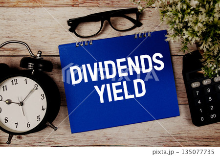 Dividends Yield text with alarm clock and calculator on wooden background 135077735