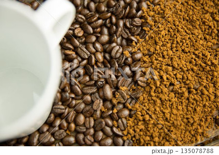 Flat design is showing overhead white ceramic coffee mug atop roasted beans blending into granules 135078788