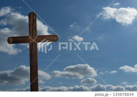 Rustic wooden cross is standing against bright blue sky with scattered white clouds, flat design Rustic wooden cross is standing against bright blue sky with scattered white clouds, flat design 135078834