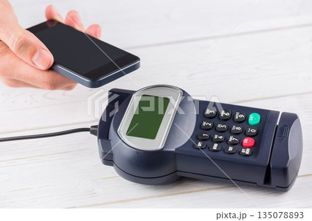 Contactless payment processing with smartphone and POS terminal in flat design on wooden countertop 135078893
