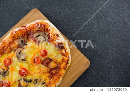 Overhead view of pizza on wooden plate Overhead view of pizza on wooden plate 135078980