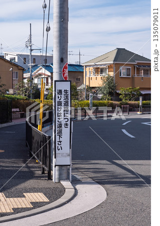 住宅街の電柱に設置された「生活道路につき通り抜けはご遠慮下さい」の注意看板と街並み 135079011