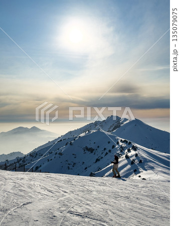 Sun over snowy mountain slope at Amirsoy ski resort. Winter landscape 135079075