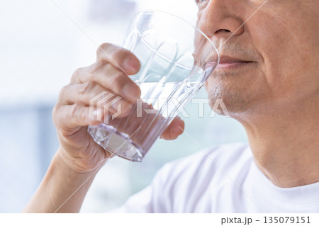 窓辺で水を飲むシニア男性 135079151