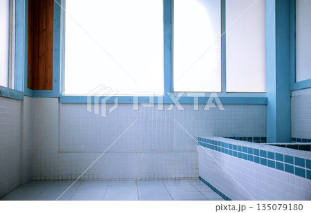Minimalist bathroom with blue and white mosaic tiles and natural light from large windows. Aesthetic vintage spa or public bath interior design for wellness concepts 135079180